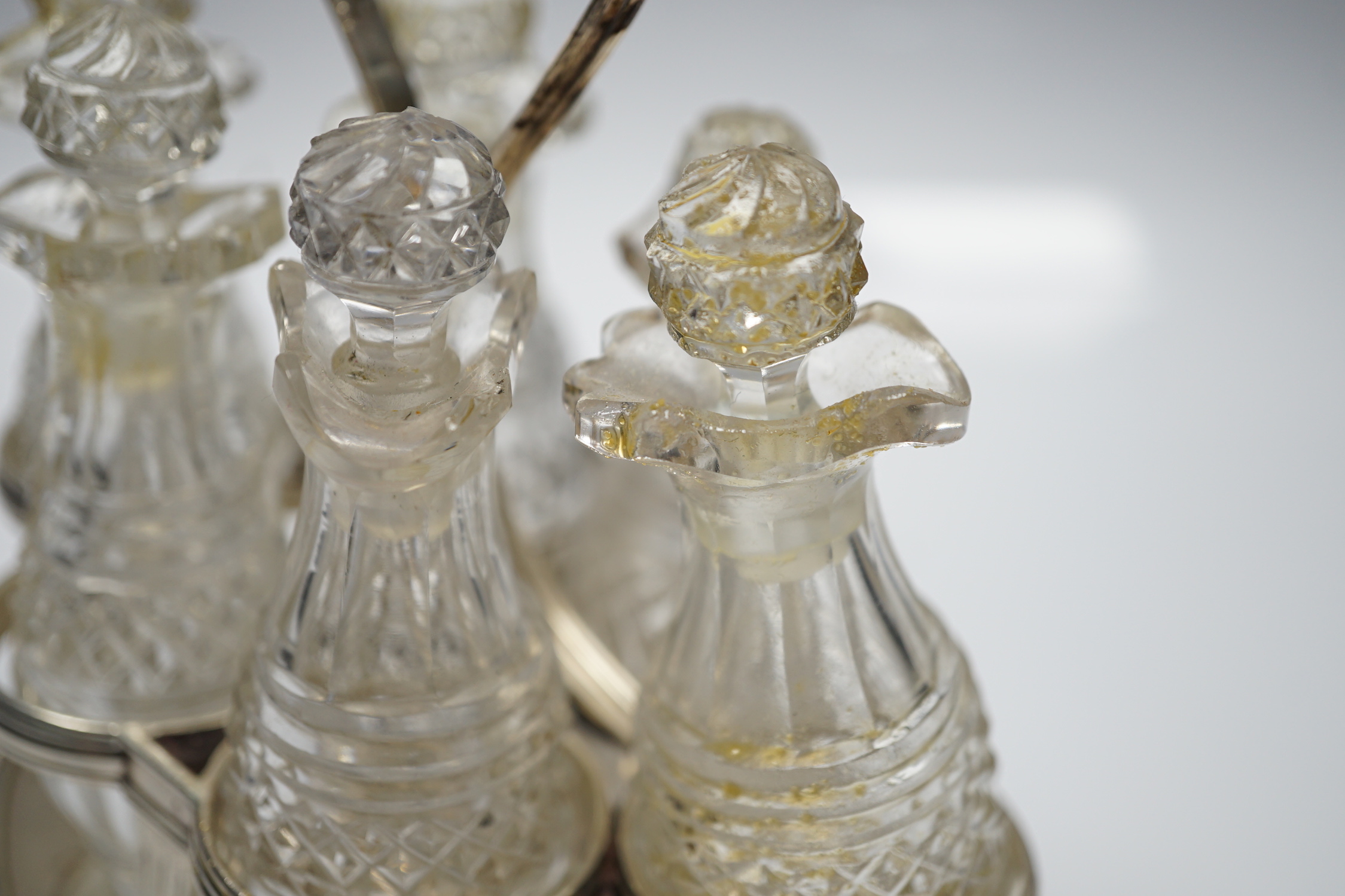A George III silver mounted oval cruet stand, maker P?, London, 1802, with reeded ring handle and gadrooned border, with six cut glass bottles and stoppers (some damage), height 20cm.